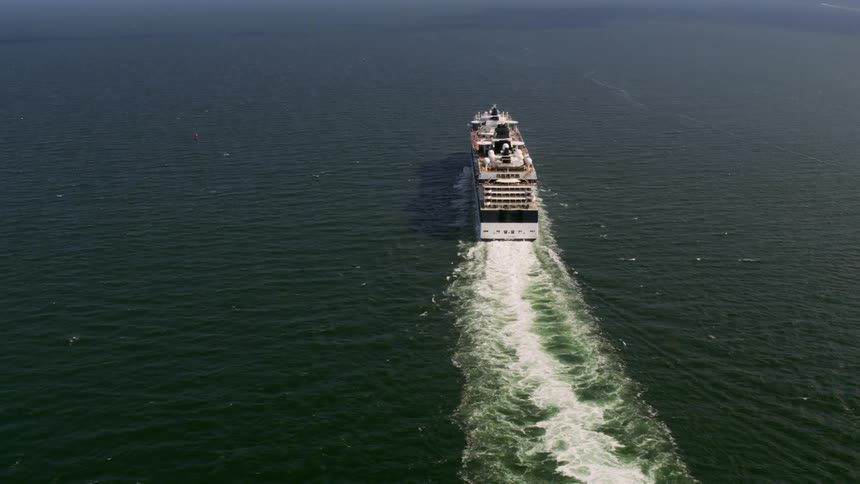 Aerial of a large cruise ship sailing across the ocean leaving waves behind it