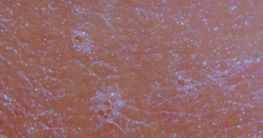 Light shines on bubbles sparkling on a pink textured surface as it twinkles