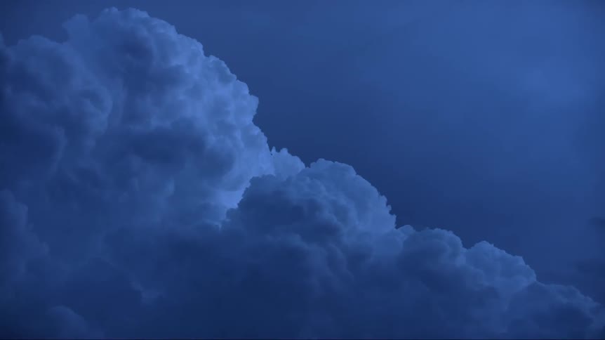Puffy blue tinted clouds roll across blue sky