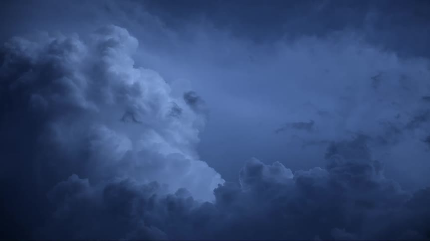 Lightning flashes illuminate clouds in a darkening sky as a storm moves in