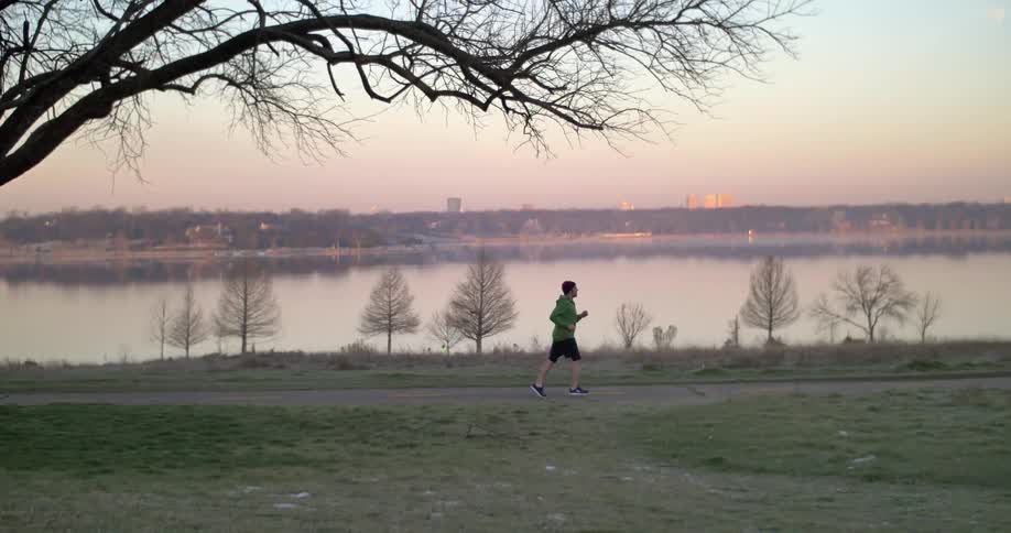 A man is jogging along a trail at sunset