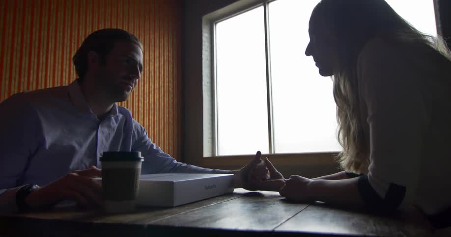 A man and woman converse while holding hands