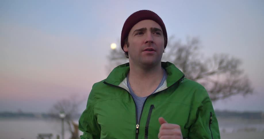 A man jogging outside on a cold day at sunset