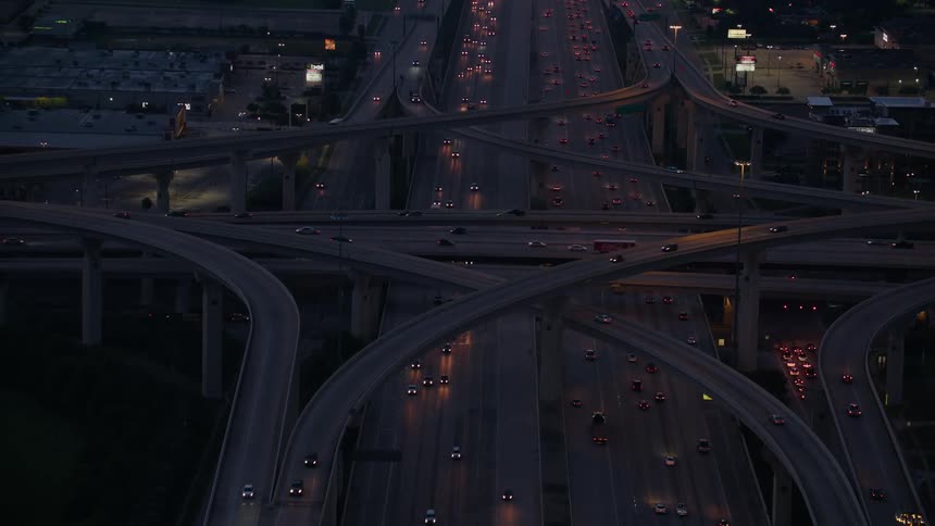 Vehicles with their lights on move along network of highways at night