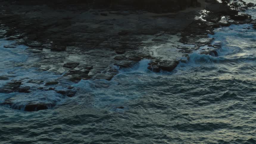 Waves crash onto rocks along the shore