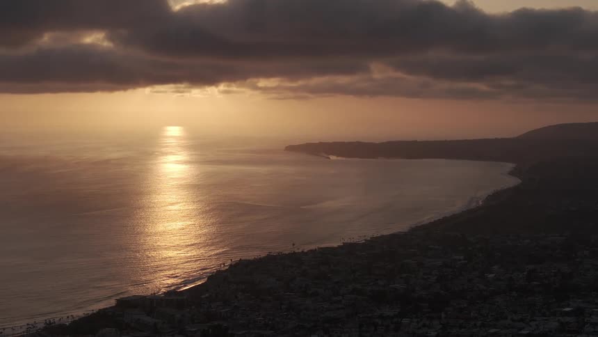 Aerial view of land being silhouetted agains the sunset near the sea