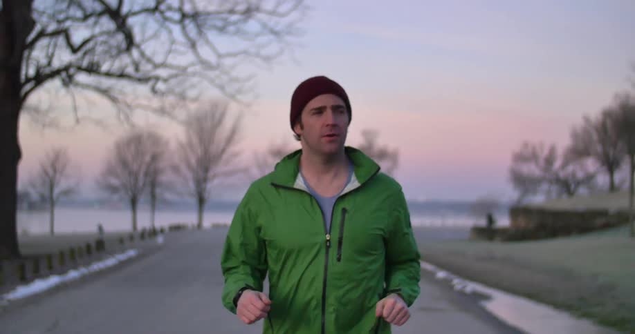 A man is jogging outside at sunset