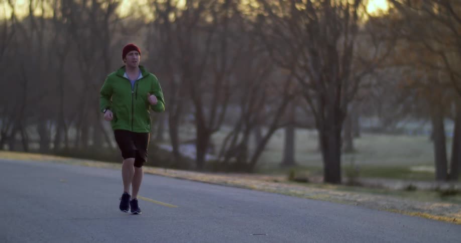 A man in a green jacket running down the street