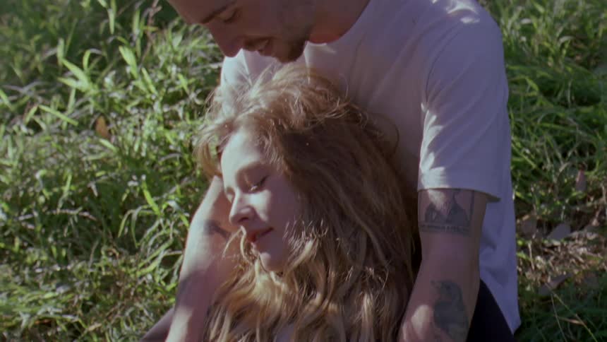 A couple sit together in the grass