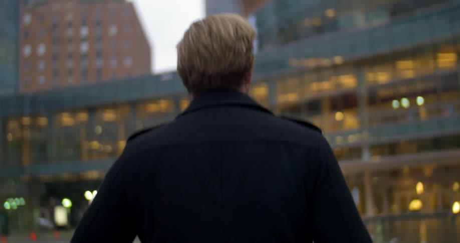 A man in a black jacket walks through a city