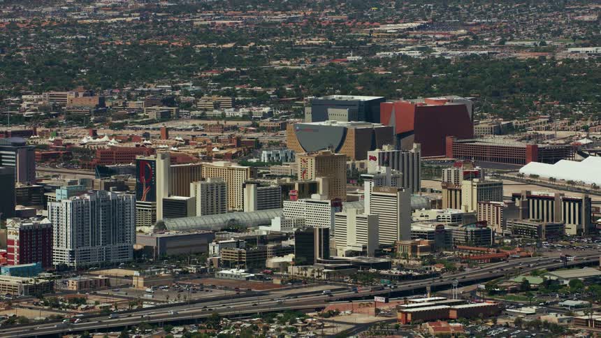 Traffic moves on highways around a big city with tall buildings surrounded by suburbs