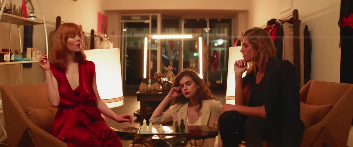Three women play chess in a boutique store at night