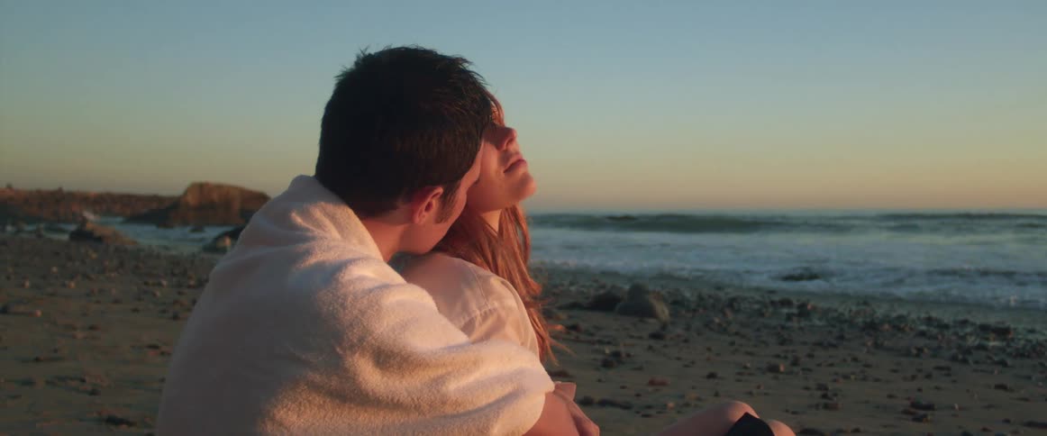 A man and woman are being affectionate at the beach