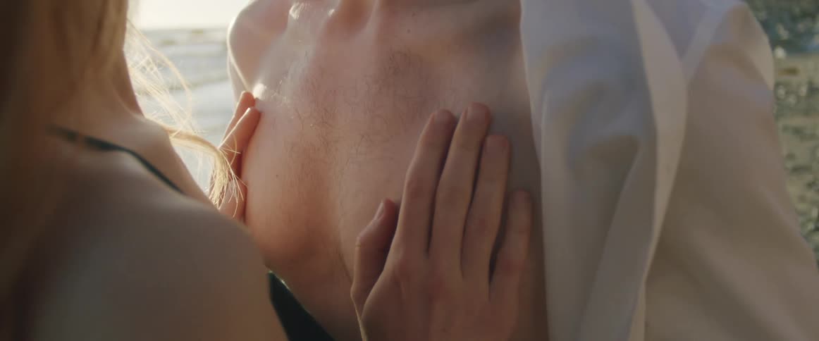 A couple on a beach kissing and caressing each other