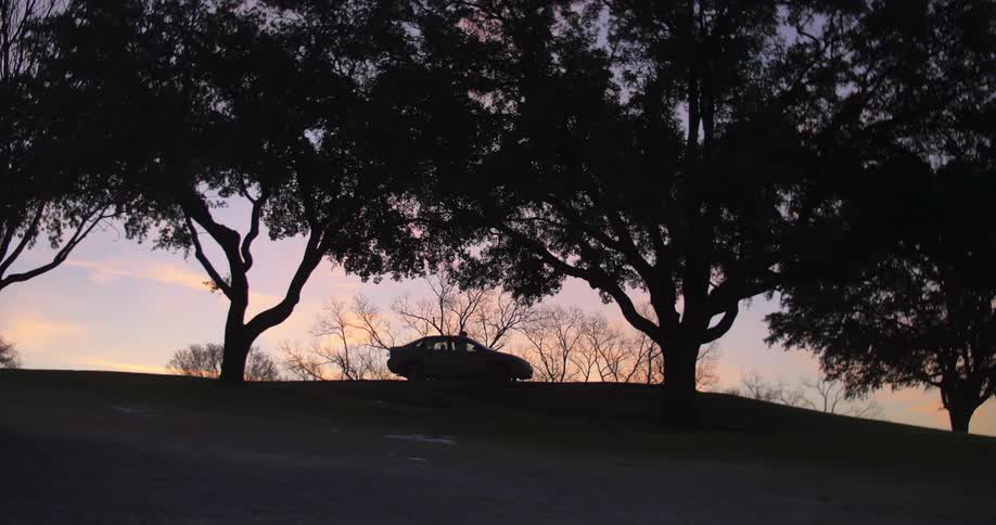 A car drives in the distance then stops at dawn