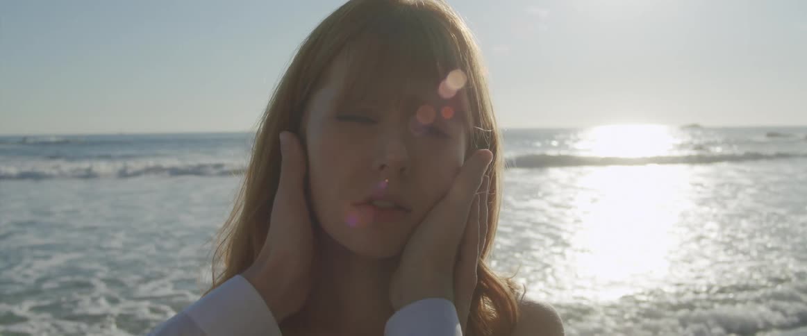 Woman gets her face caressed by a man near the waves on a beach