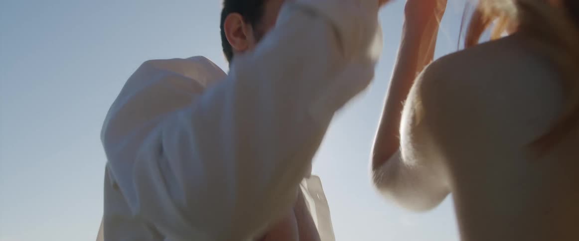 Man takes womans hand and brings her to face him on beach in romance novel cover style
