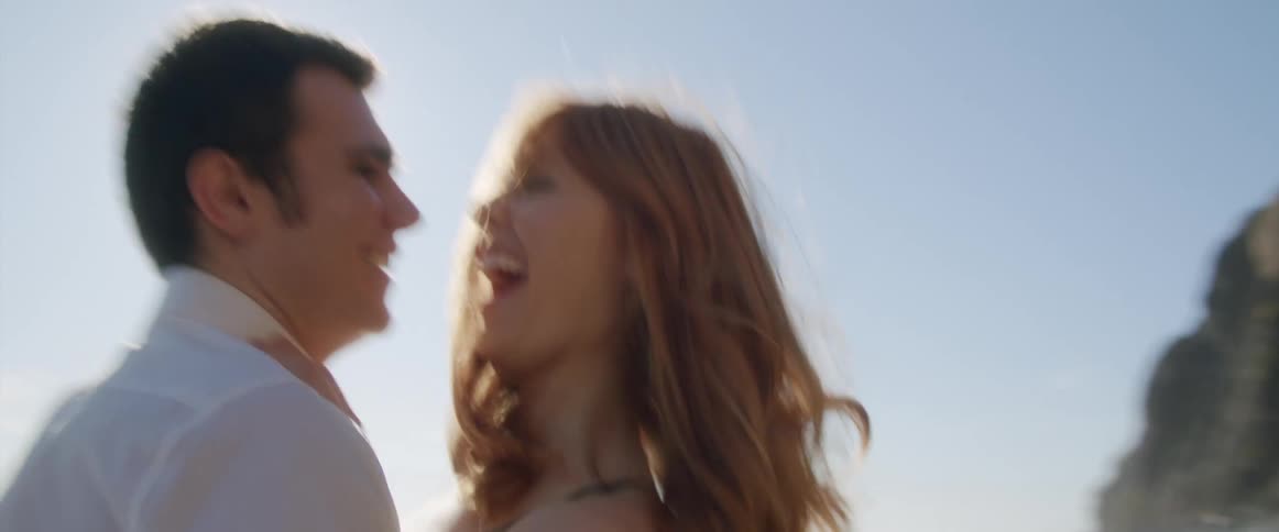 A man picks up his girlfriend and spins her around on the beach