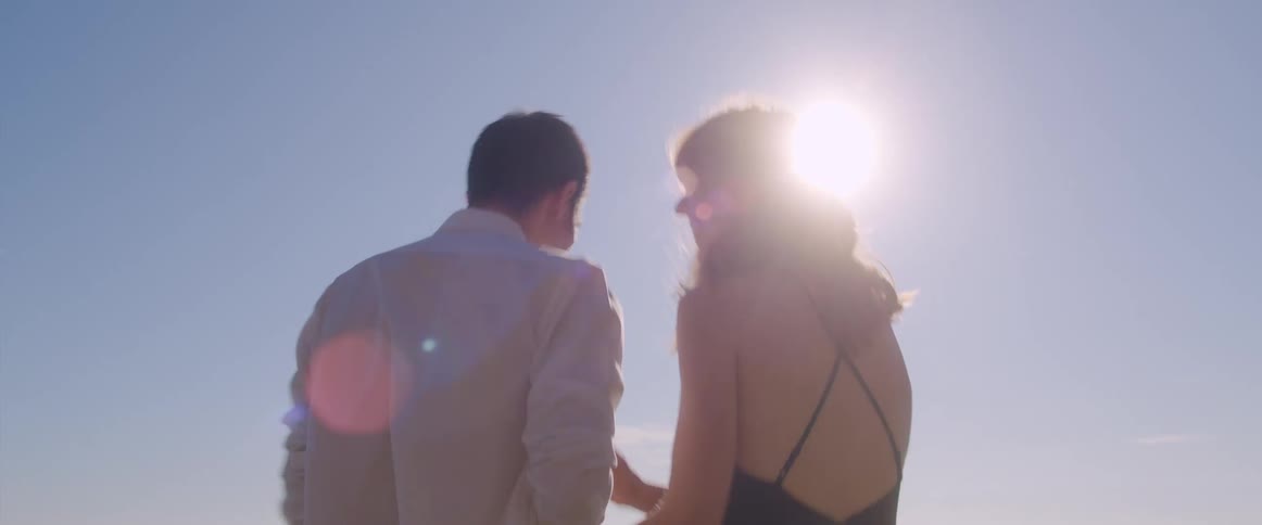 Young couple in formal attire walk on the beach holding hands at morning