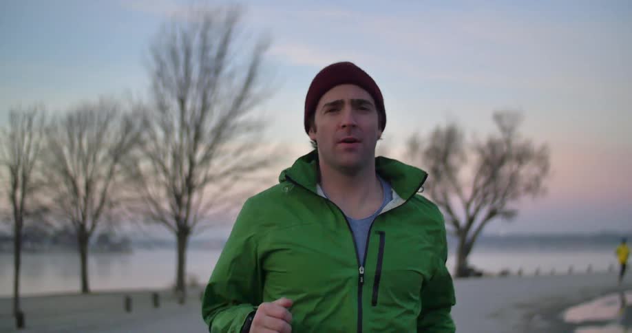 A man jogging near a beach at sunset