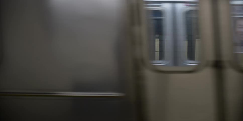 An empty subway train leaves a station with an empty platform
