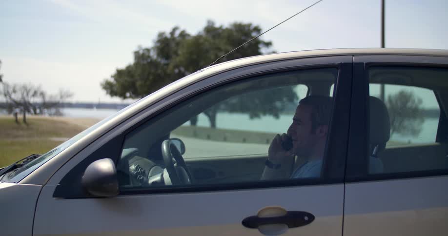 A man opens his phone and dials in a car
