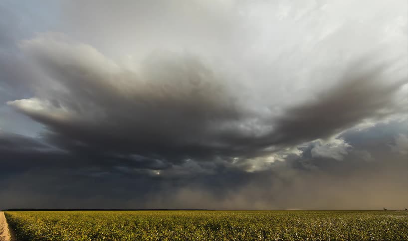 A field has some storm clouds pouring rain and heavy winds