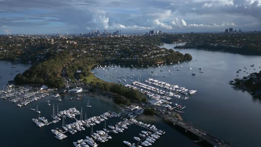 Traffic flows through marina toward neighborhood with city downtown in the distant background
