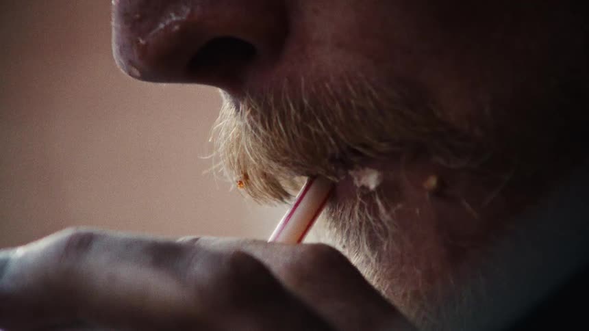 Man drinks using a straw holding cut with dirty hand and chewing while food smears his mustache and beard