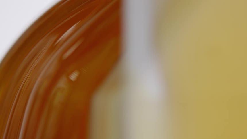 Amber honey flows slowly down side of container