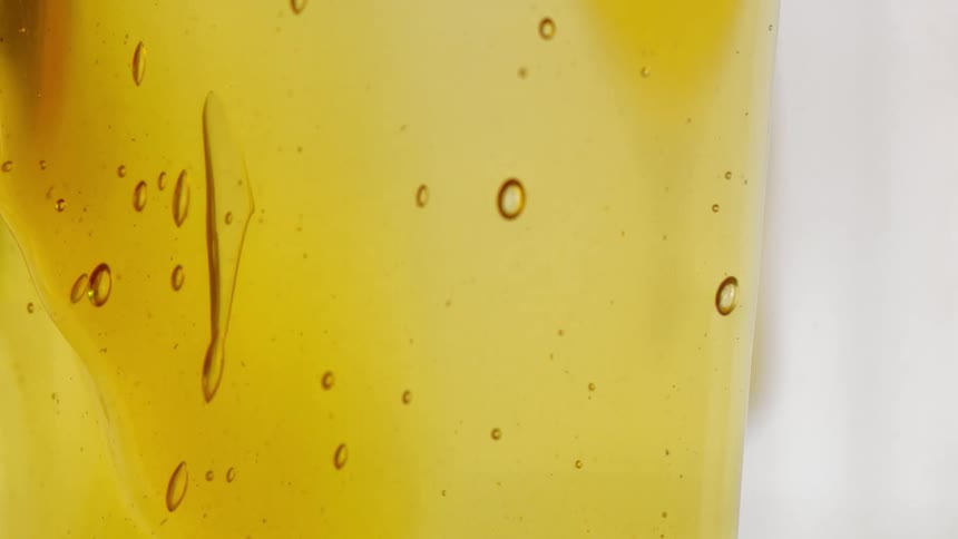 Thick yellow syrup flows inclear container