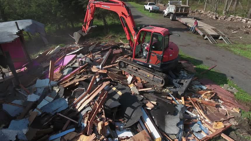 An excavator destroys a house