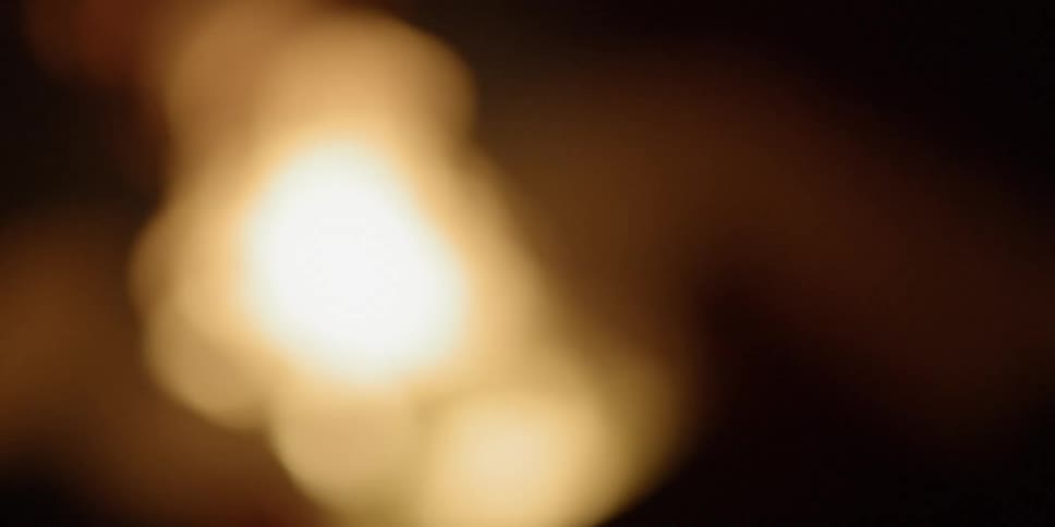 The camera out of focus looks towards a fire