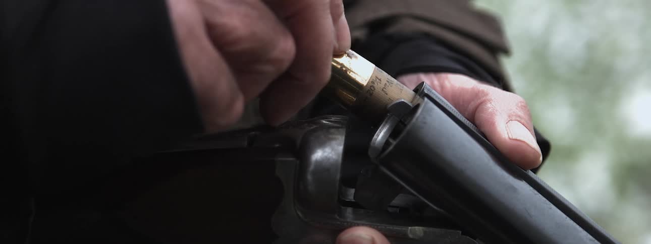 Someone is loading a shotgun with shells