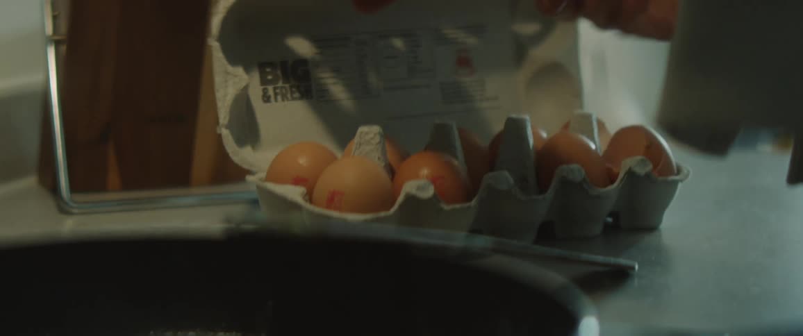 Woman takes an egg from box and cracking it in the kitchen