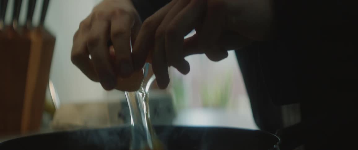 A person at home cracks an egg in to a frying pan