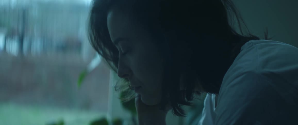 Close up of a woman sitting looking contemplatively she she flips her hair back with her hand