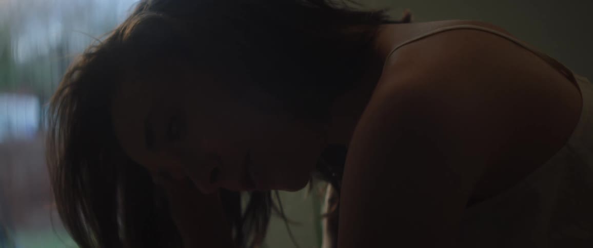 Tired woman with white top and brown hair yaws in bedroom