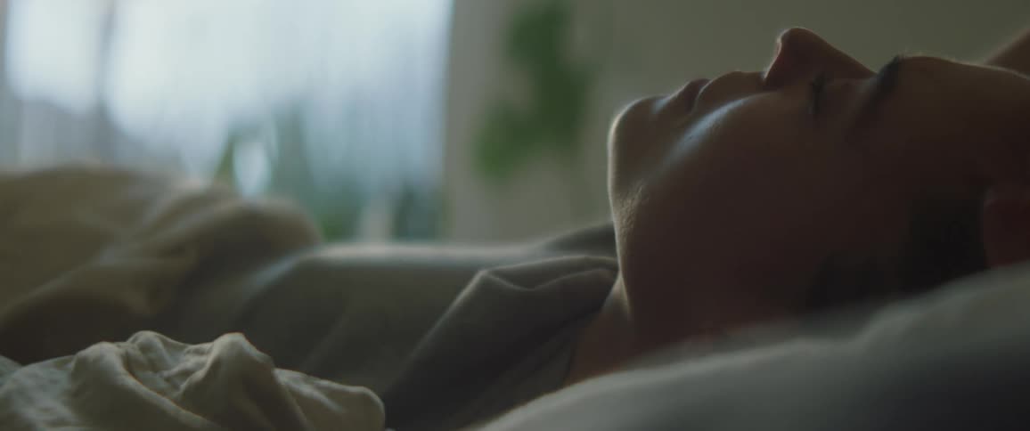 Waking woman turns in bed and stretches