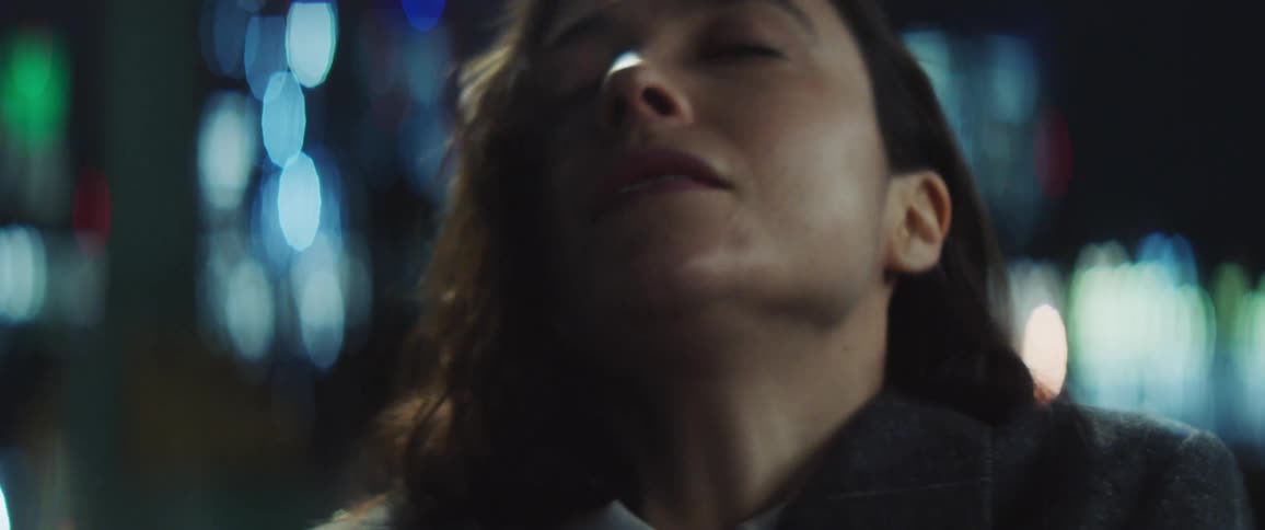 A close up of a womans face as she rolls her head around and looks sensually