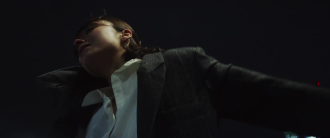The view is of a young woman dancing downtown at night time