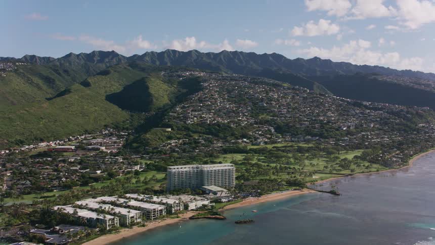 Drone view of a suburban neighborhood on a coastline with mountain ranges in the distance