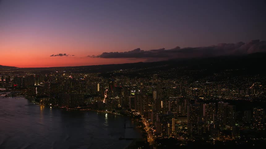 A coastal city with a mountain range in the background at night