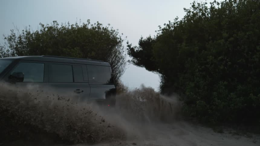 A vehicle splashes mud as it drives through a puddle