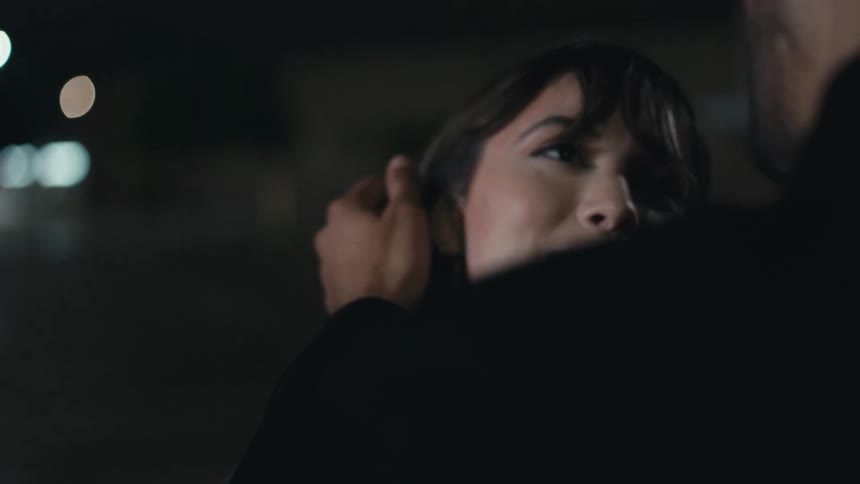 Man gently touches womans cheek smiling and talking at the parking lot