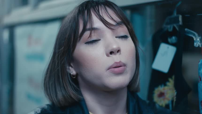Woman with earrings and bob haircut talks to person next to clothing store