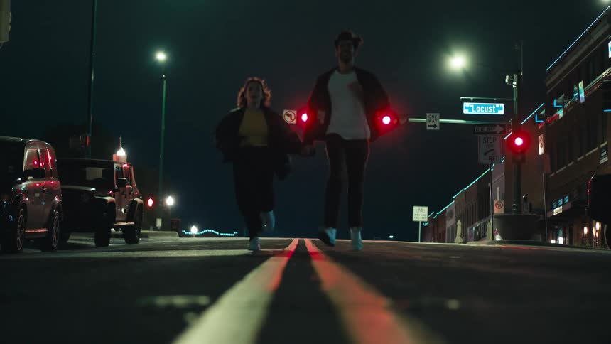 A couple runs on a road while holding hands