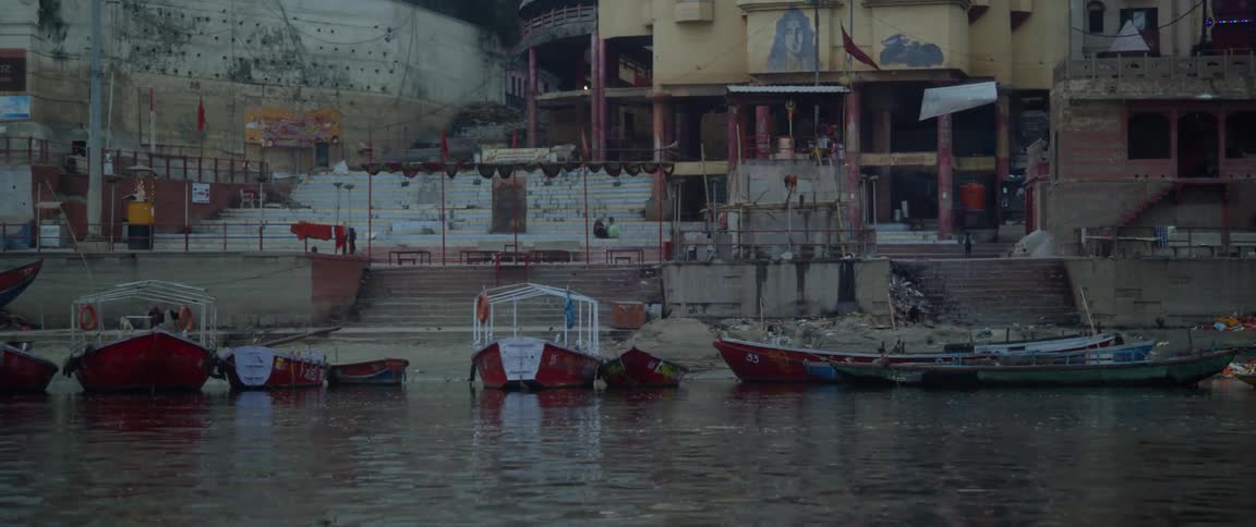 Canoes and kayaks are parked along the coast in a developing city