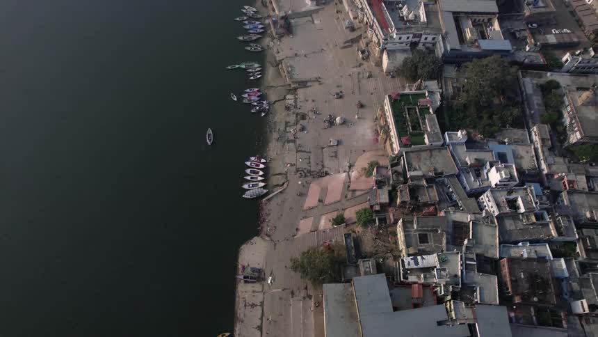 Kayaks and canoes sit parked along the shore of a city