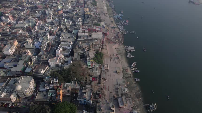 A dirt pier in a third world city by a body of water